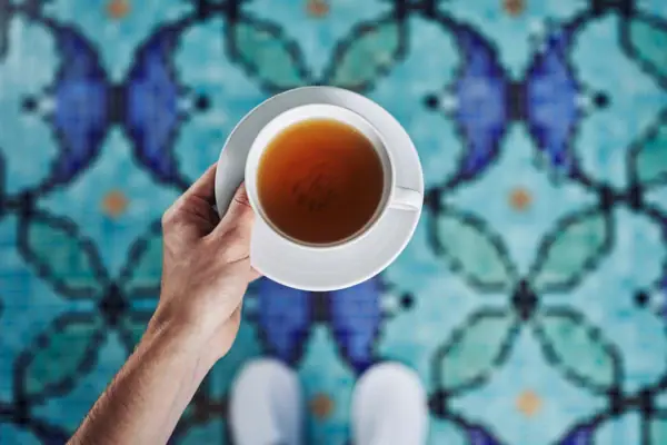 Tee Eine Hand hält eine Teetasse.