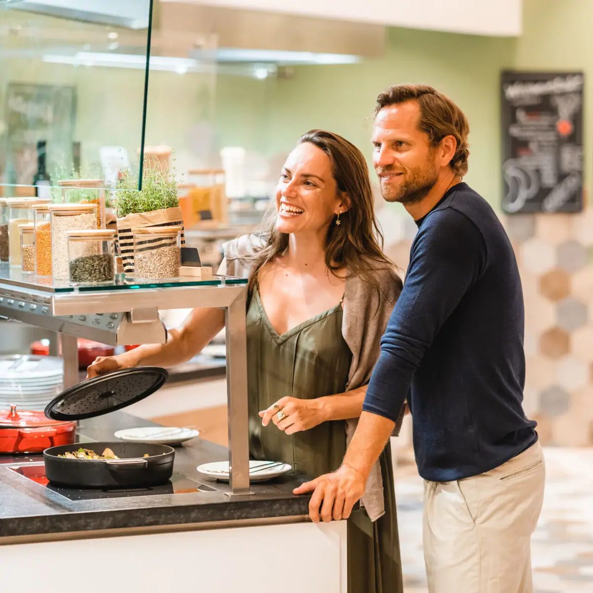 A man and a woman are standing next to a counter with food.