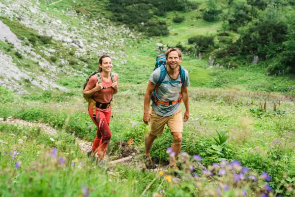 A woman and a man hike along a small path through a mountain world.