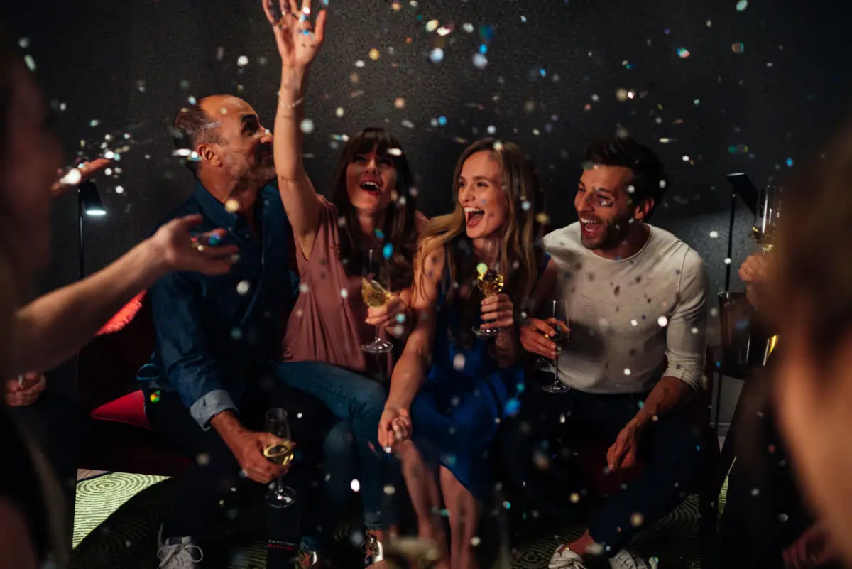 A group of people sit on the floor while confetti falls.