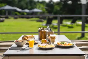 Ein Frühstückstisch mit Essen darauf auf einer Terrasse im Grünen.