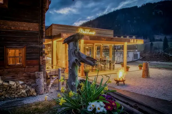 A building with a fire pit and a tree stump in front of it.