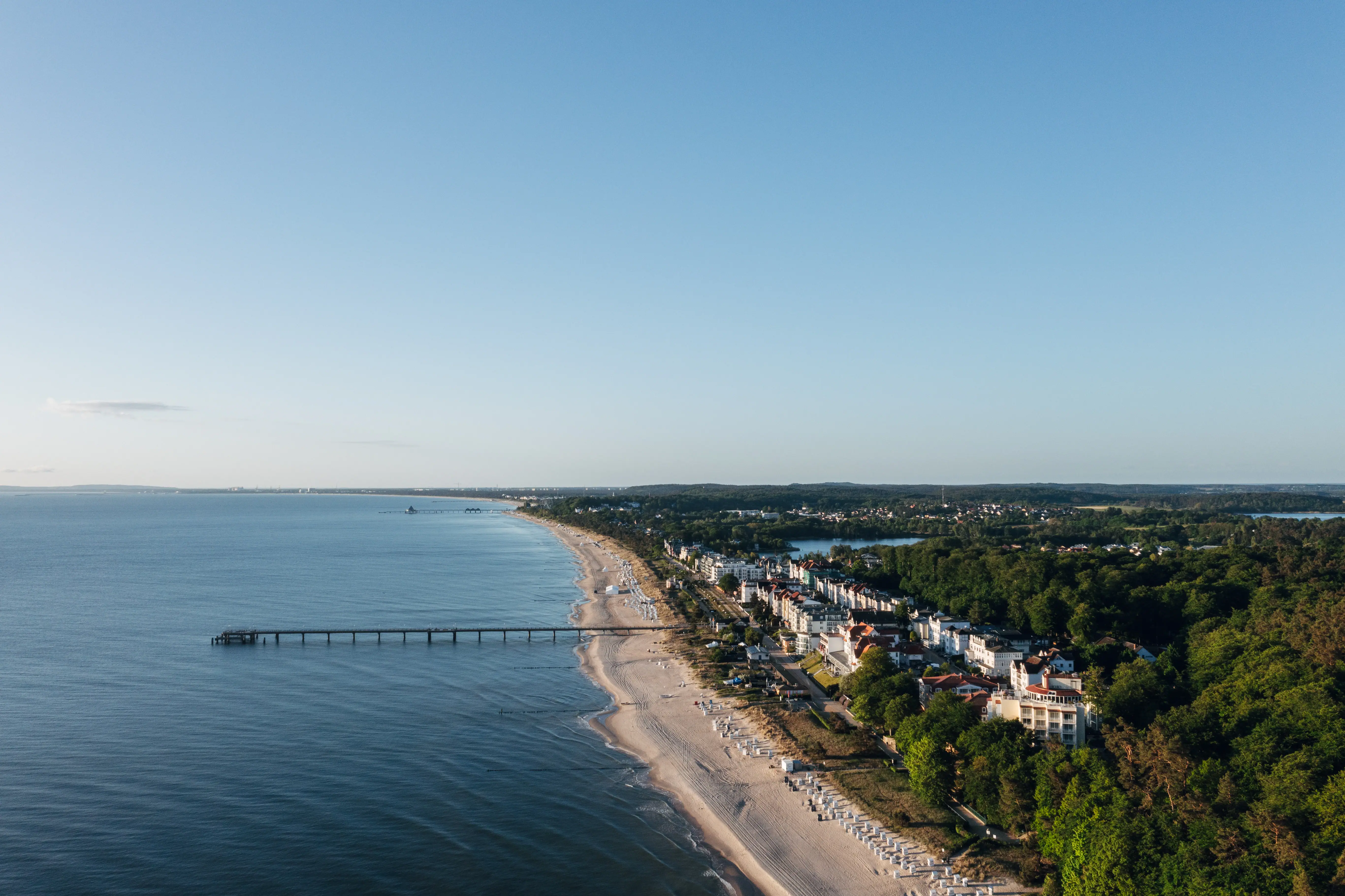 Beach with a pier and buildings in the background.