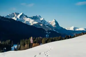 A person stands in the snow in a wintry mountain landscape.