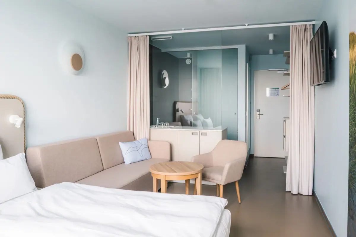 Rooms at the aja Travemünde A room with a sofa and a table.
