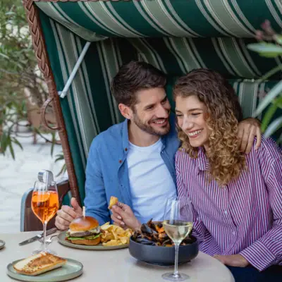 Bistro & Bar Patio A man and a woman are sitting at a table with food and drinks.