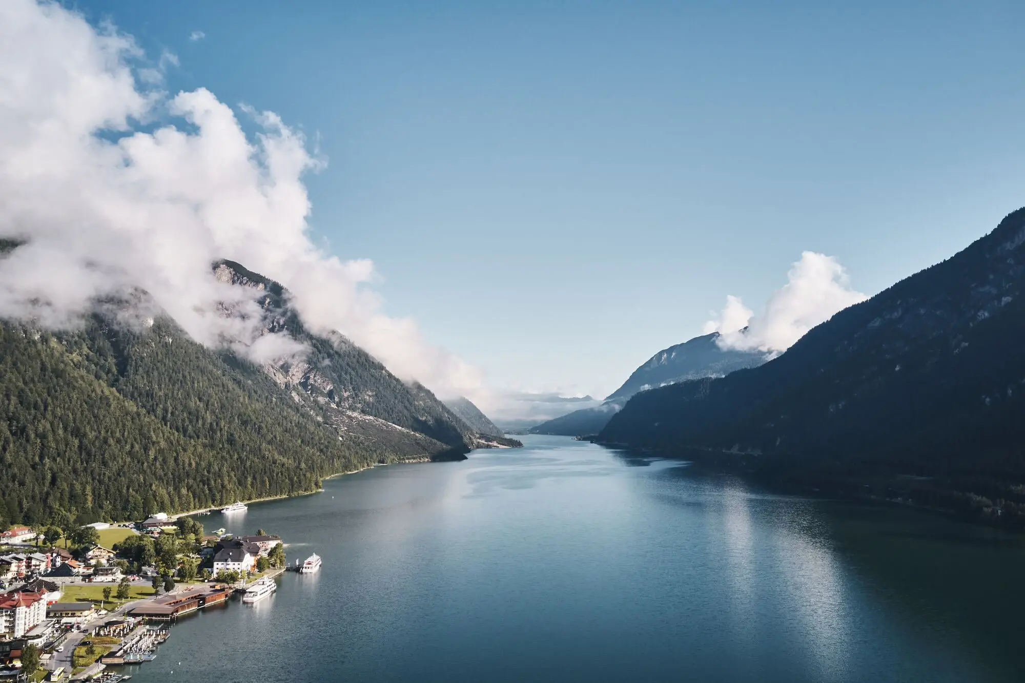 Lake Achensee A body of water with a house and mountains in the background.