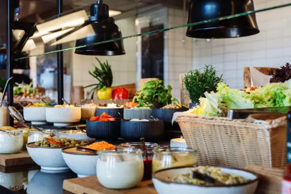 Salad bar Buffet table with various food items and tableware.