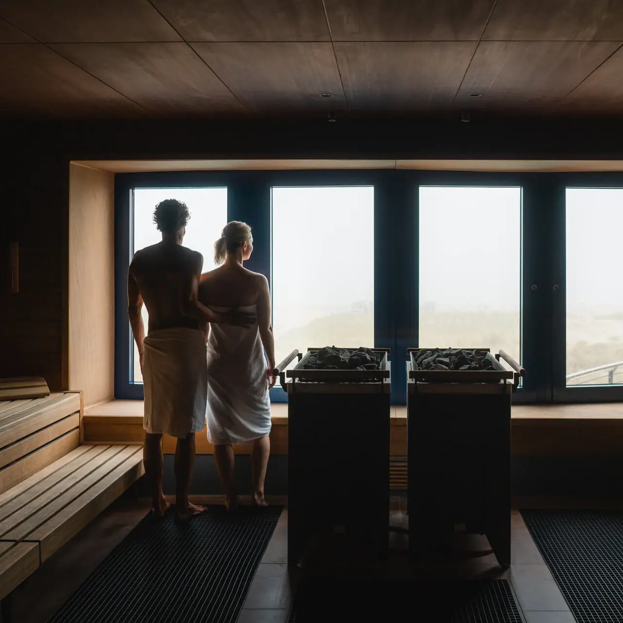 A man and a woman are standing in a sauna.