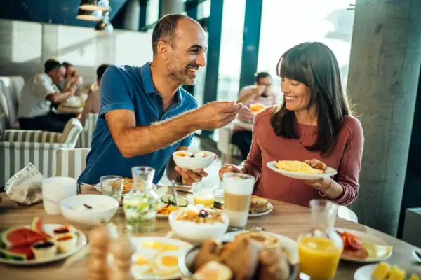 A man and a woman are eating at a table.