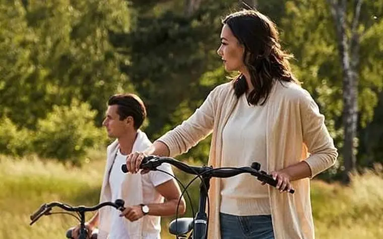 A man and a woman with bicycles in a field.