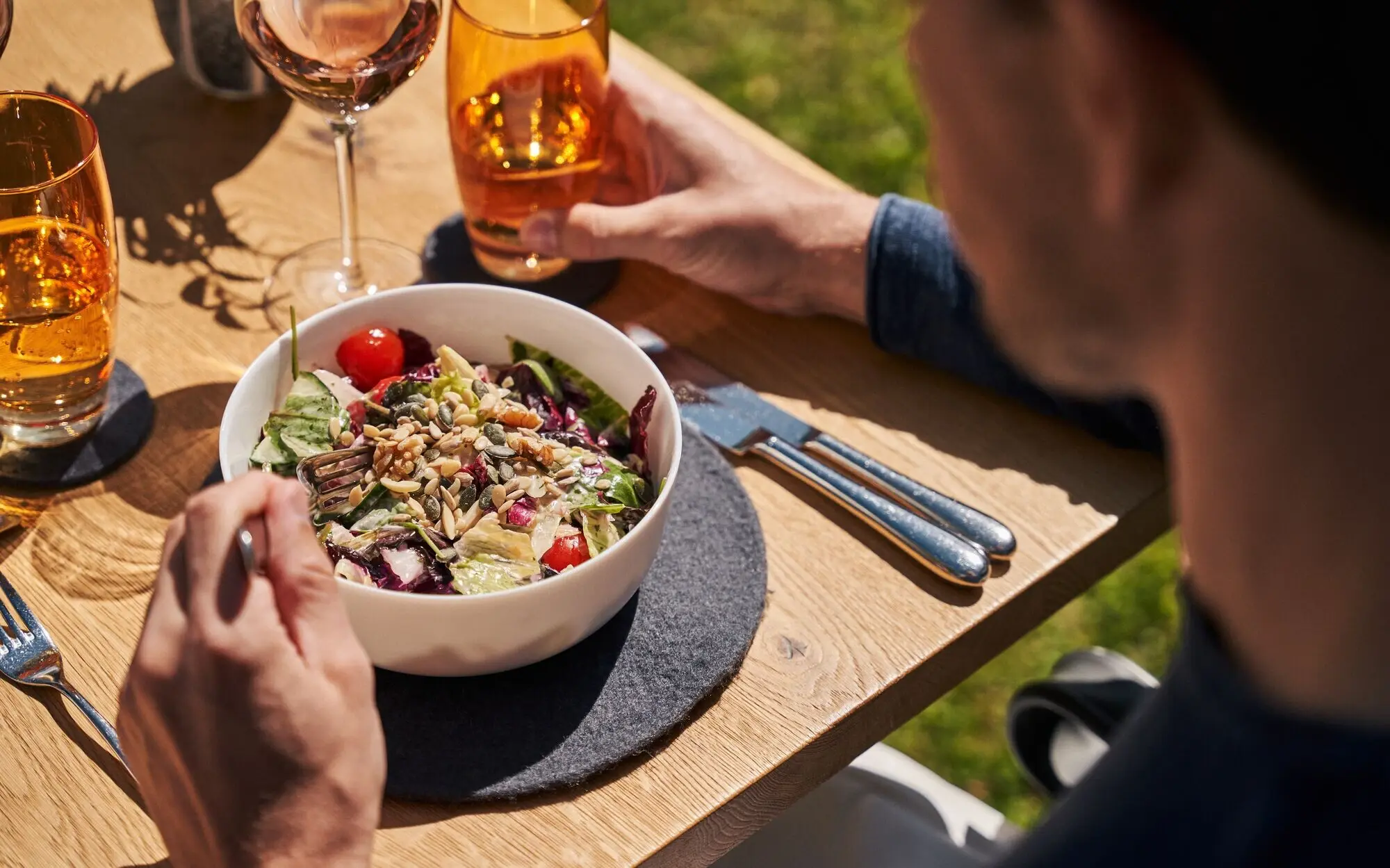 Man eating salad and drinking wine at the table.