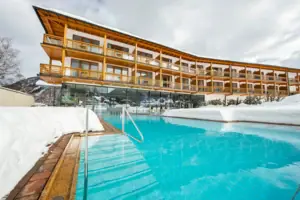 A swimming pool in front of a building, with a clear sky in the background.