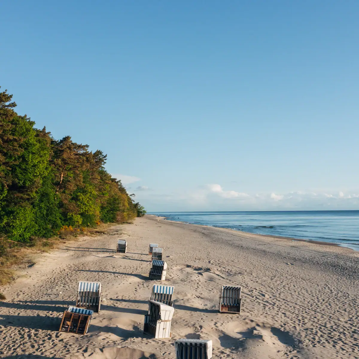 Chairs on the beach with a view of the water and the sky.