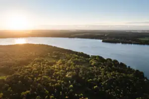 Ein Gewässer mit Bäumen und einer Stadt in der Ferne.