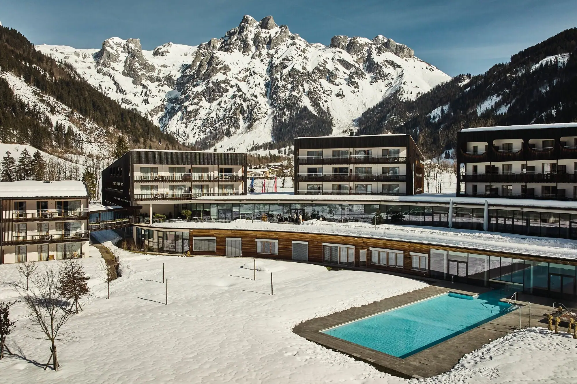 A pool in front of a building with mountains in the background.
