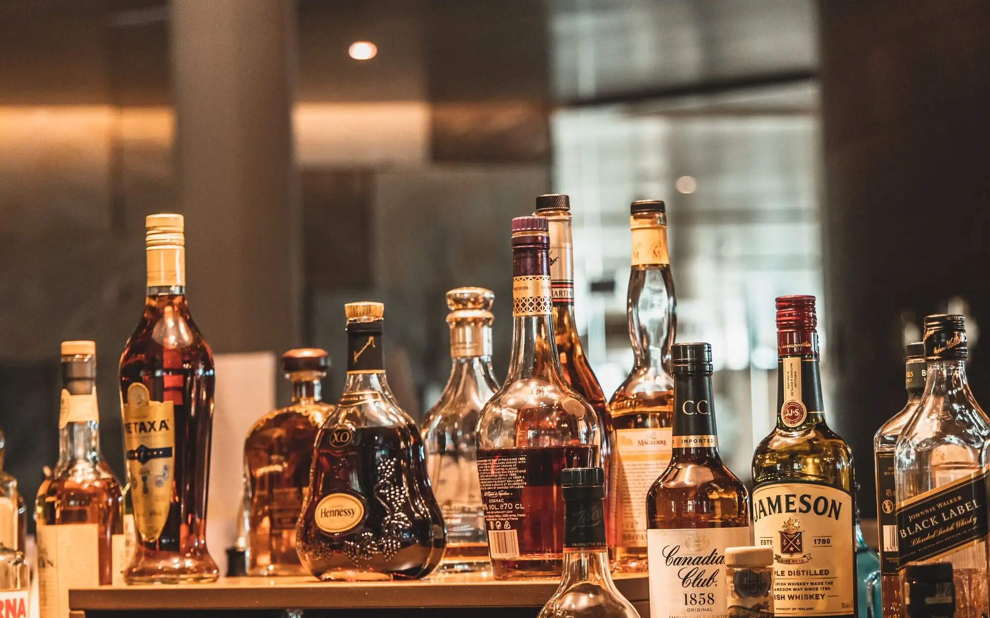 Group of alcohol bottles on a counter in a bar.