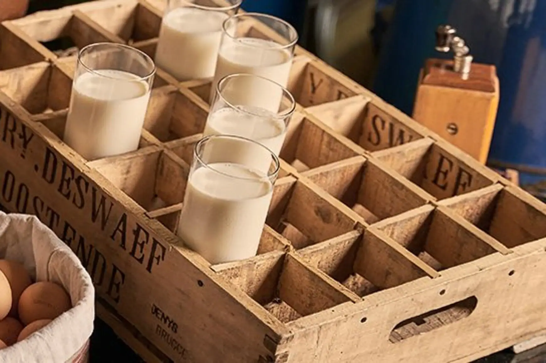 Bread and eggs in a basket next to a glass of milk