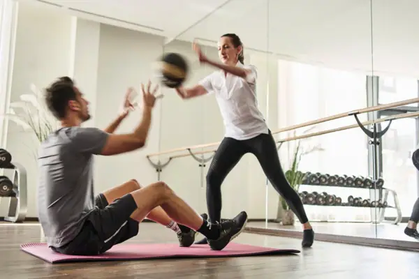 A man and a woman work out in a gym.