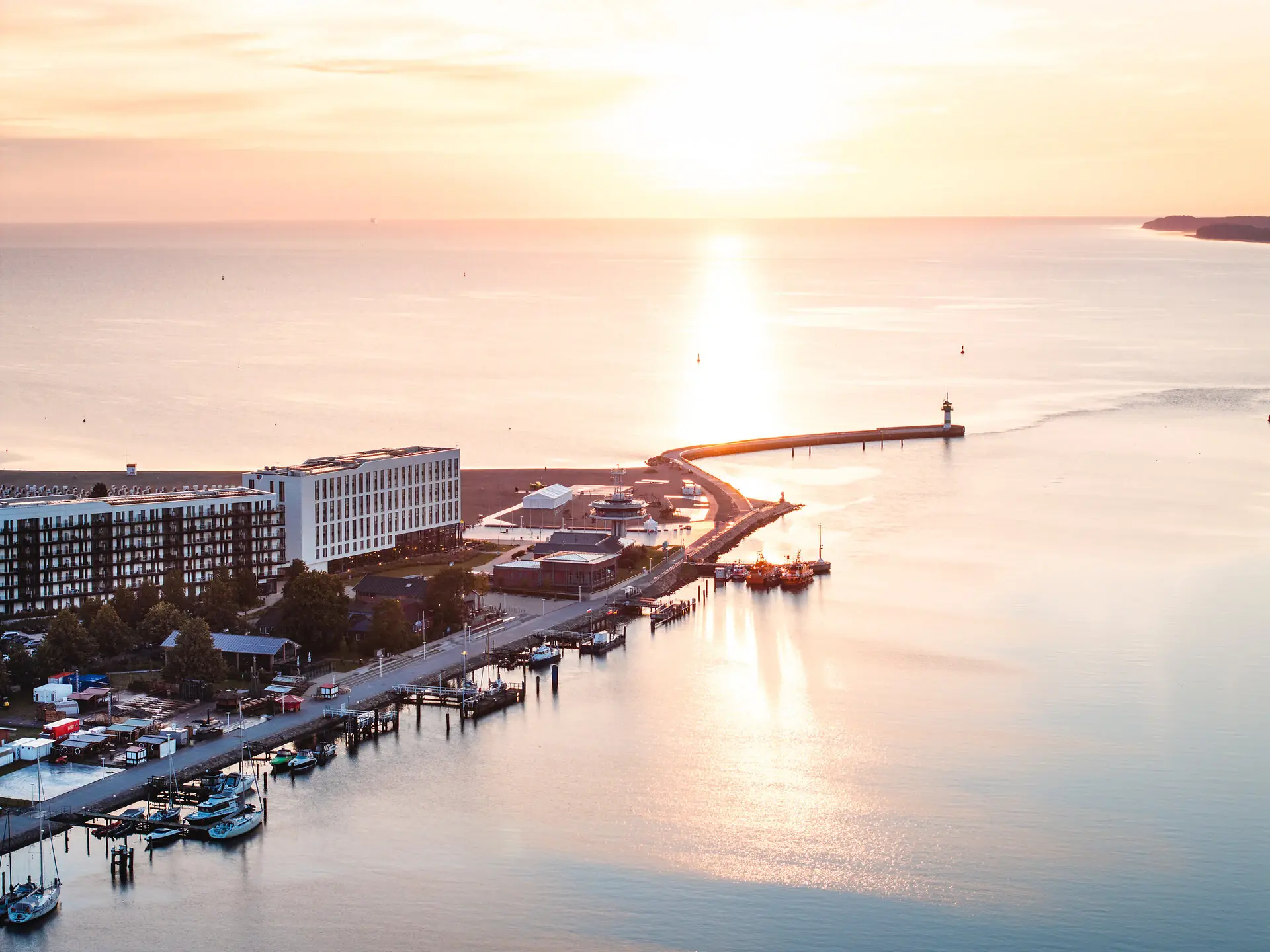 Pier extending into a body of water with nearby buildings at sunrise.