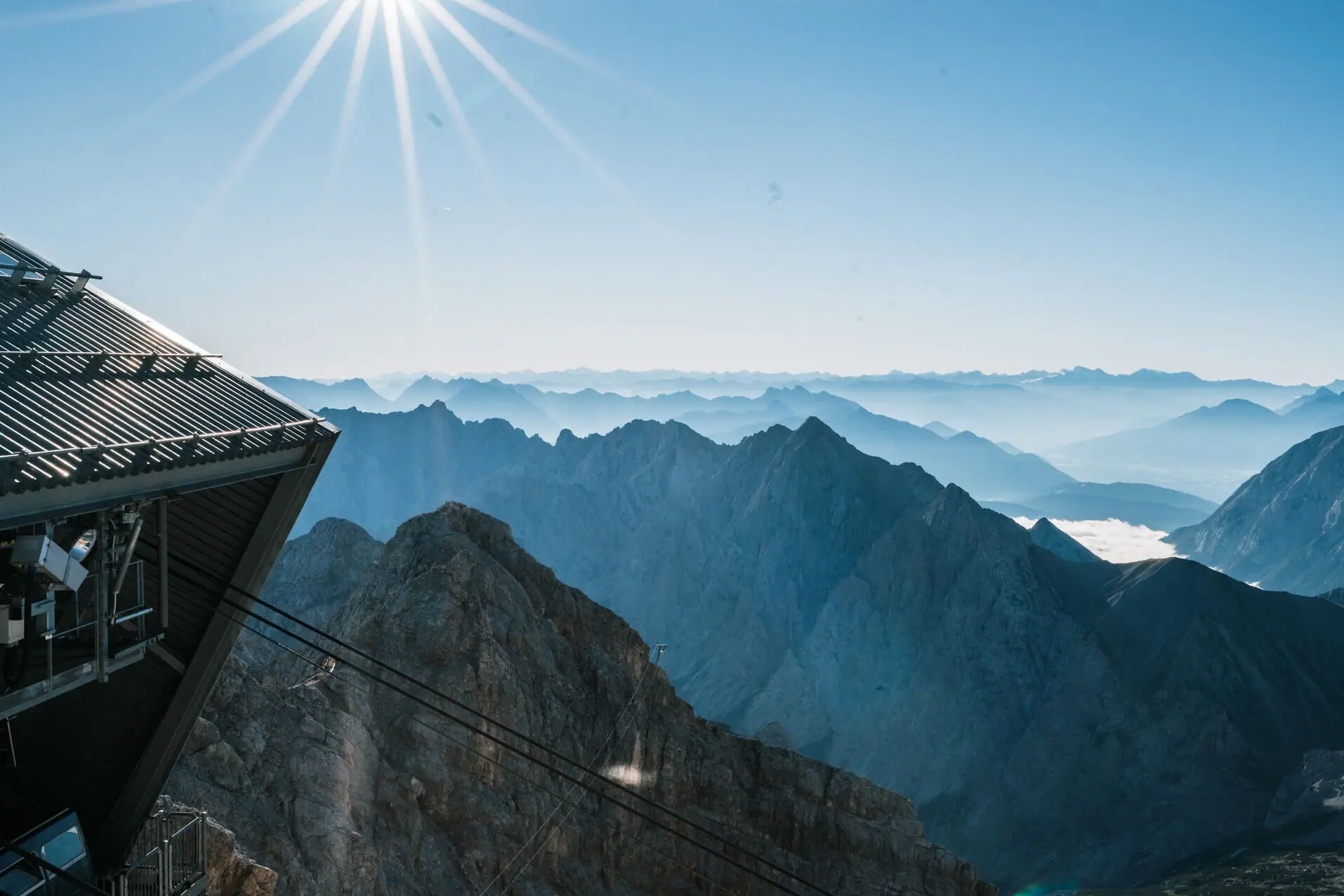 A mountain massif with a cable car and bright sunshine.