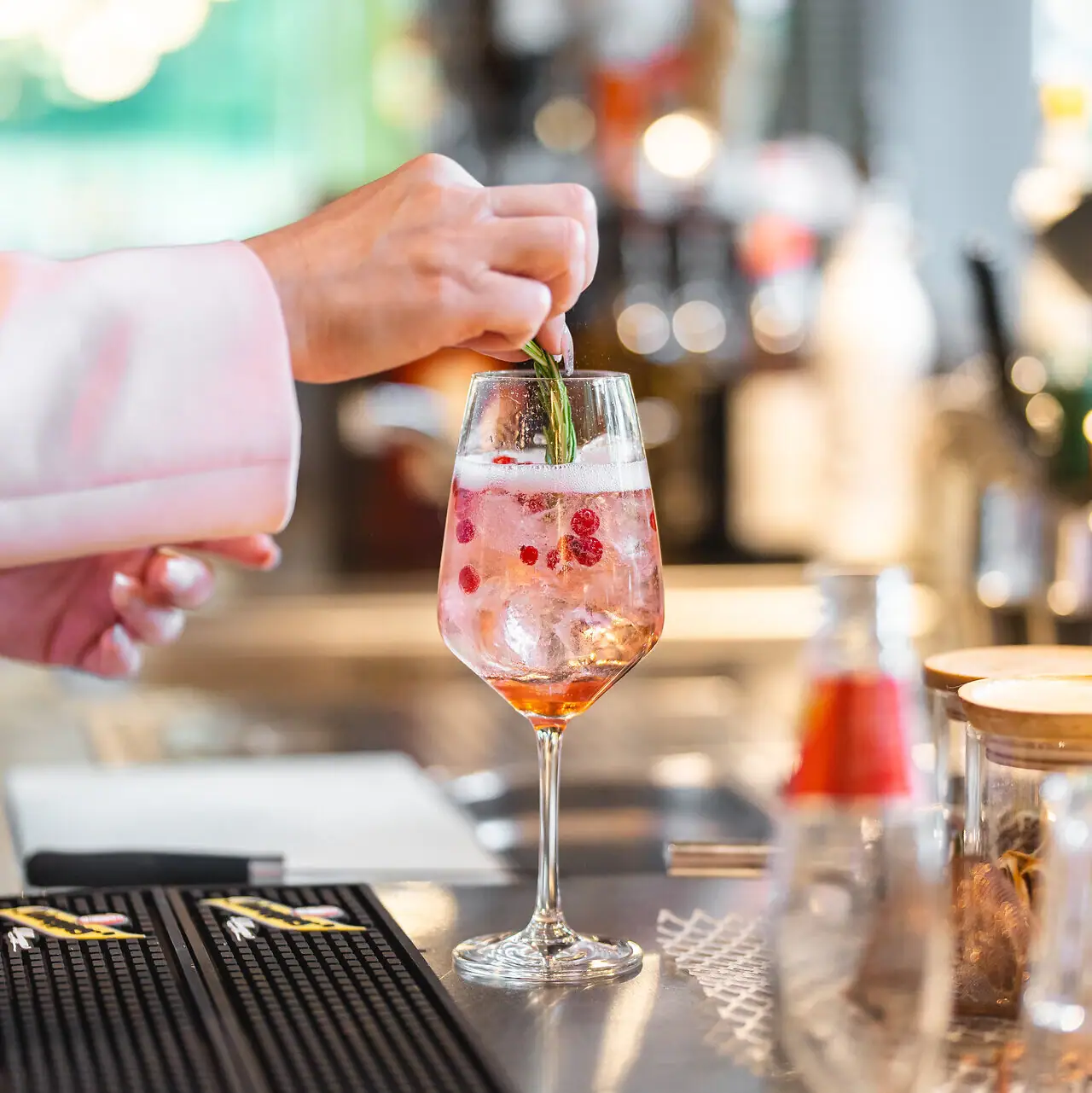 One person places a leaf on a drink in a glass.