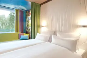 Ein Hotelzimmer mit weißen Betten und bunten Vorhängen.