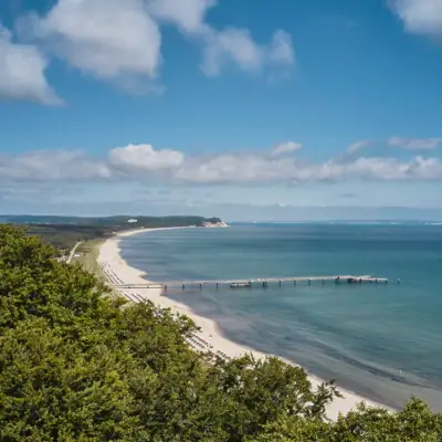 Göhren A beach with a pier and trees.
