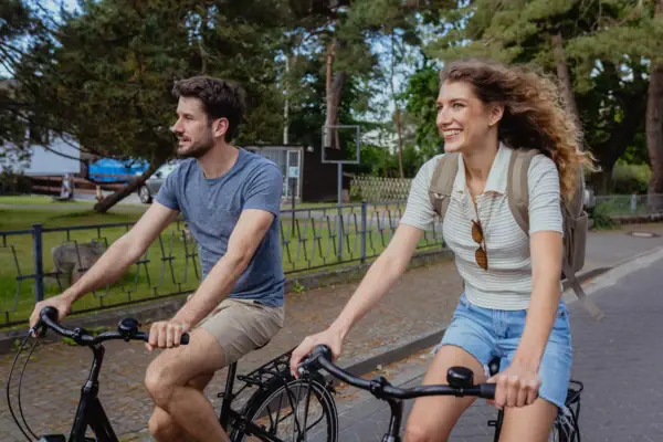 A man and a woman ride bicycles.