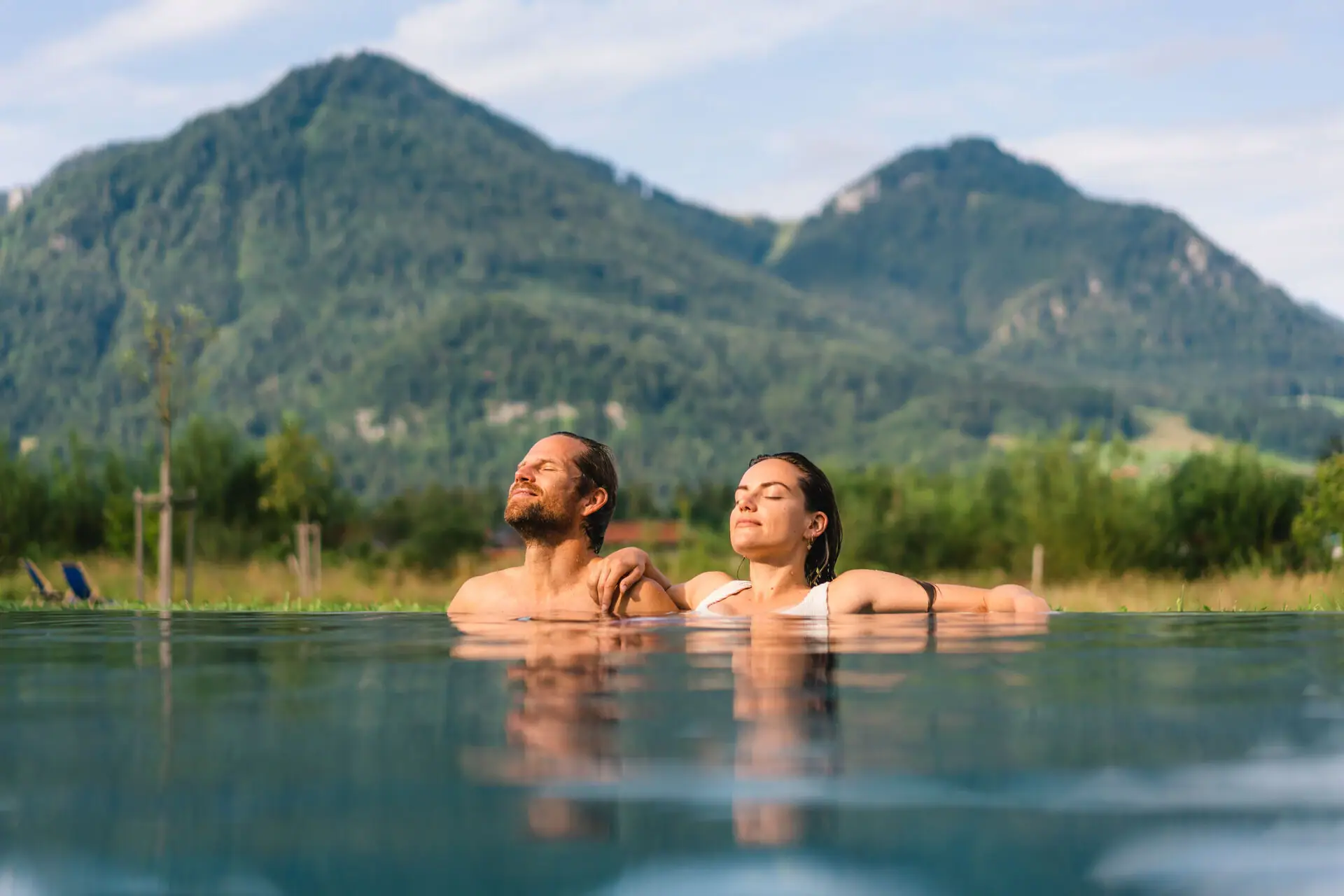 Relaxed time out A man and a woman in a pool with mountains in the background.
