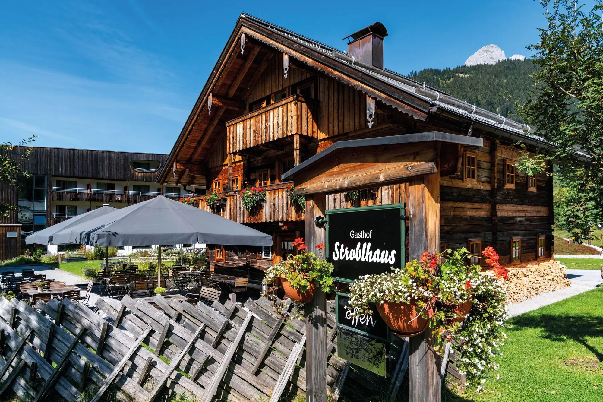 The Stroblhaus restaurant in a wooden house with a sign in front of it.