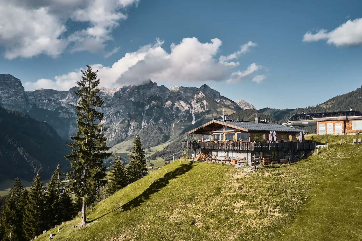 Hut on a hill with mountain landscape in the background.