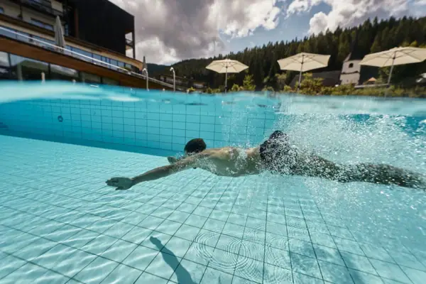A man dives in the outdoor pool at the aja Werfenweng.