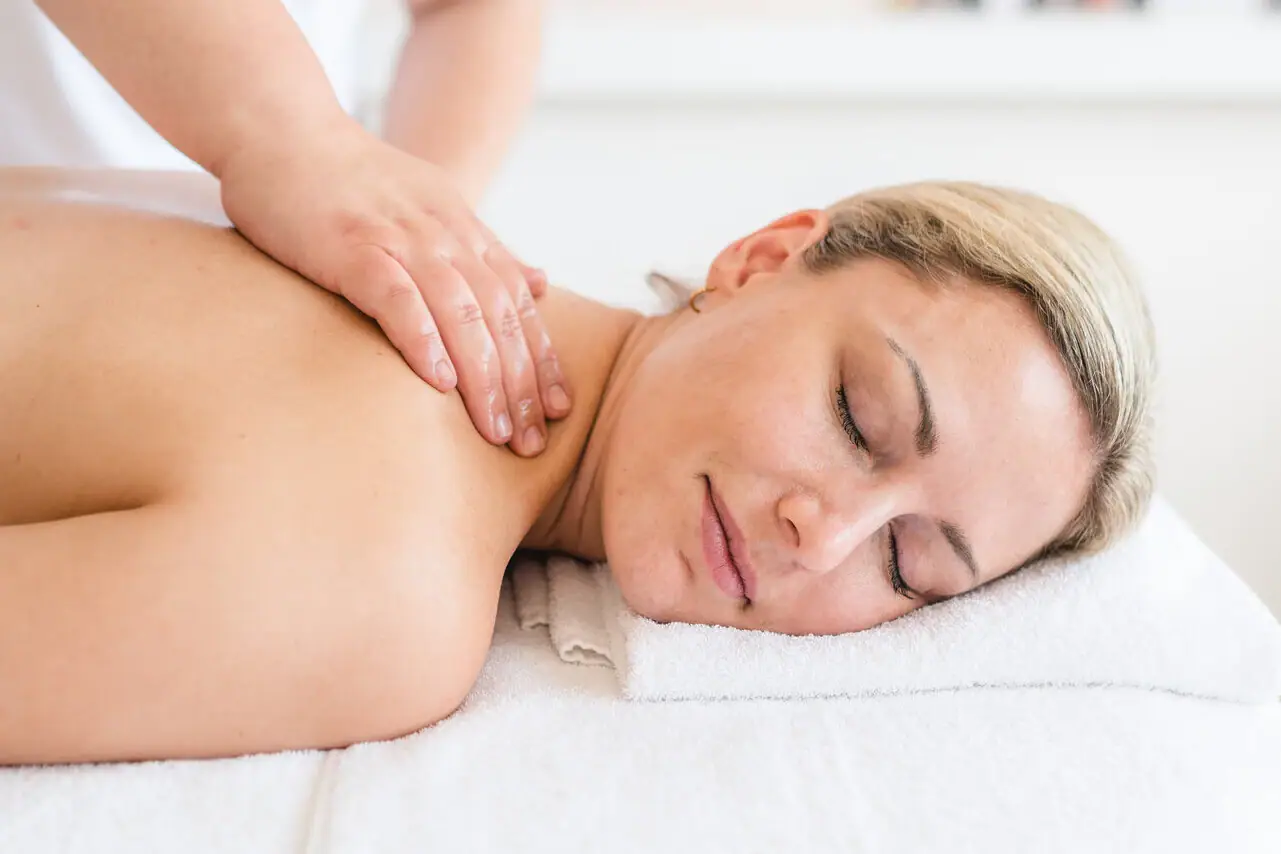 Massage A woman lies on a white towel with her eyes closed.