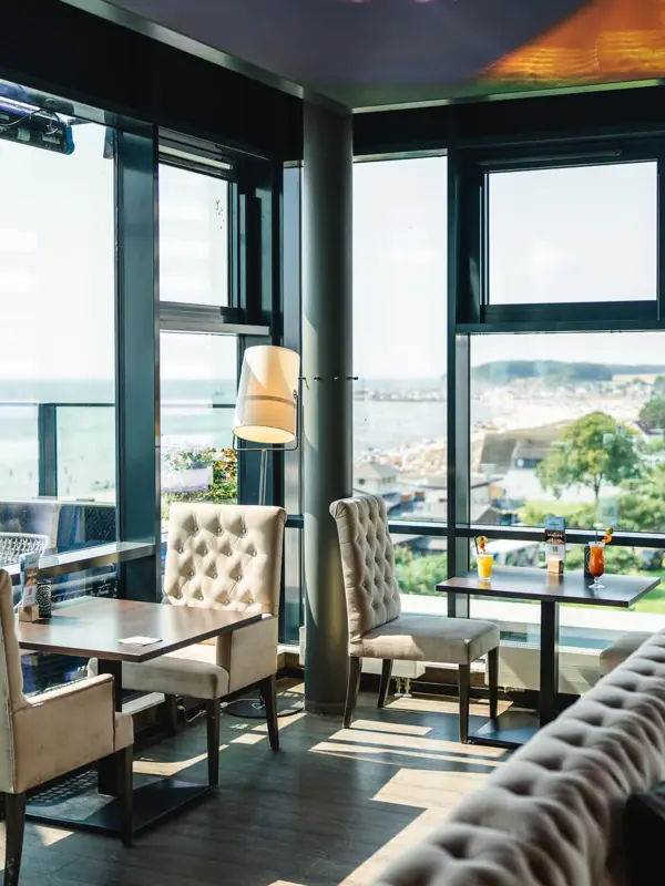 Ein Raum mit einem großen Fenster, Tischen und Stühlen.