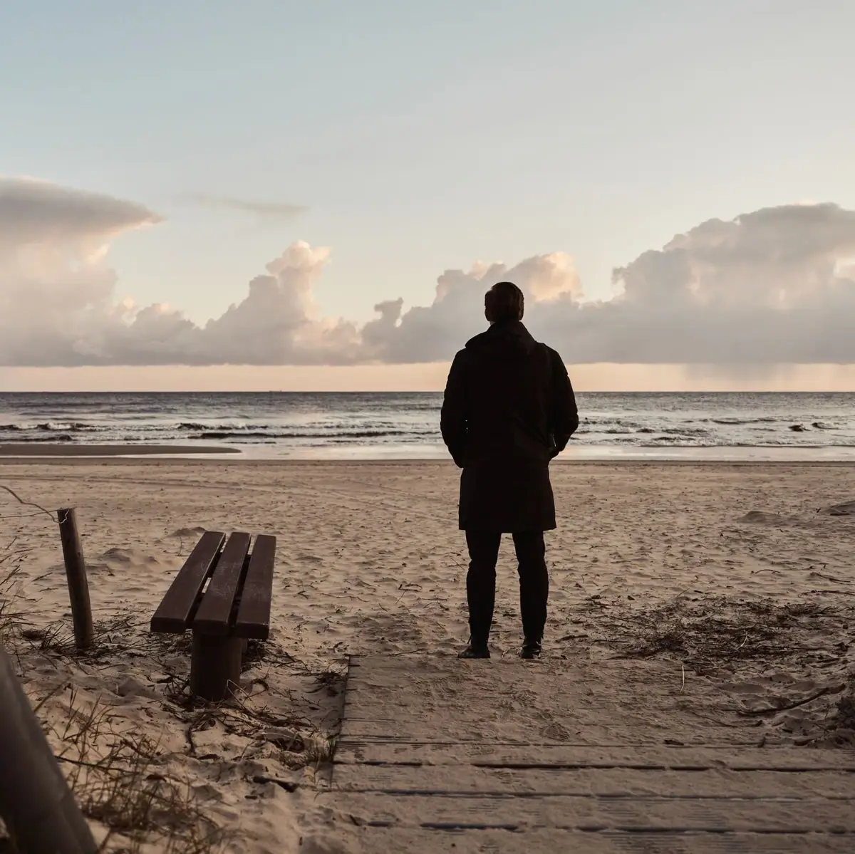 A person stands on the beach and looks out to sea.