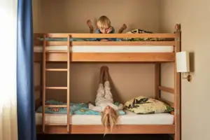 A boy is lying on a bunk bed on which a girl is also lying.