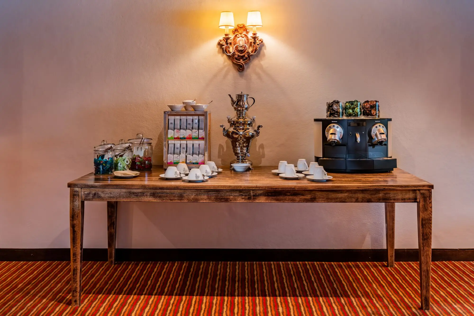 A large coffee machine, tea selection and cups on a table.