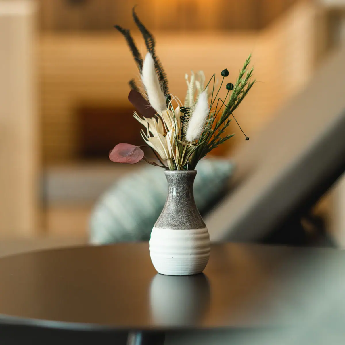 A vase with dried flowers on a table.