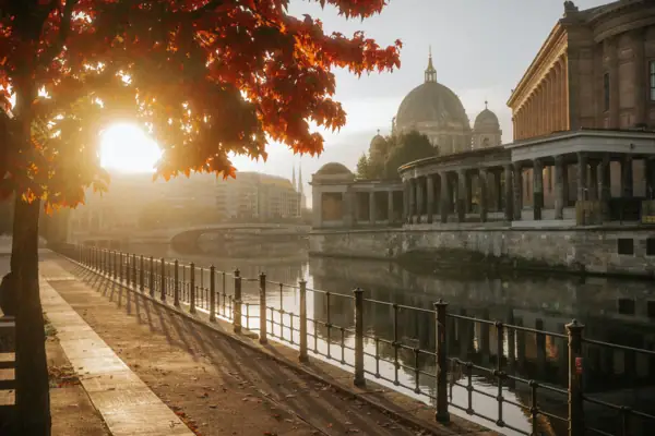 A body of water with a walkway and a building with a dome.