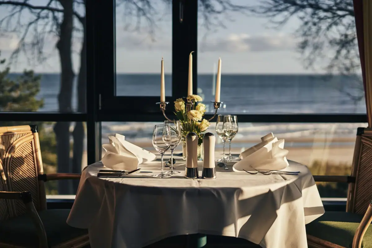 A festively laid table with crockery, wine glasses and a tablecloth.