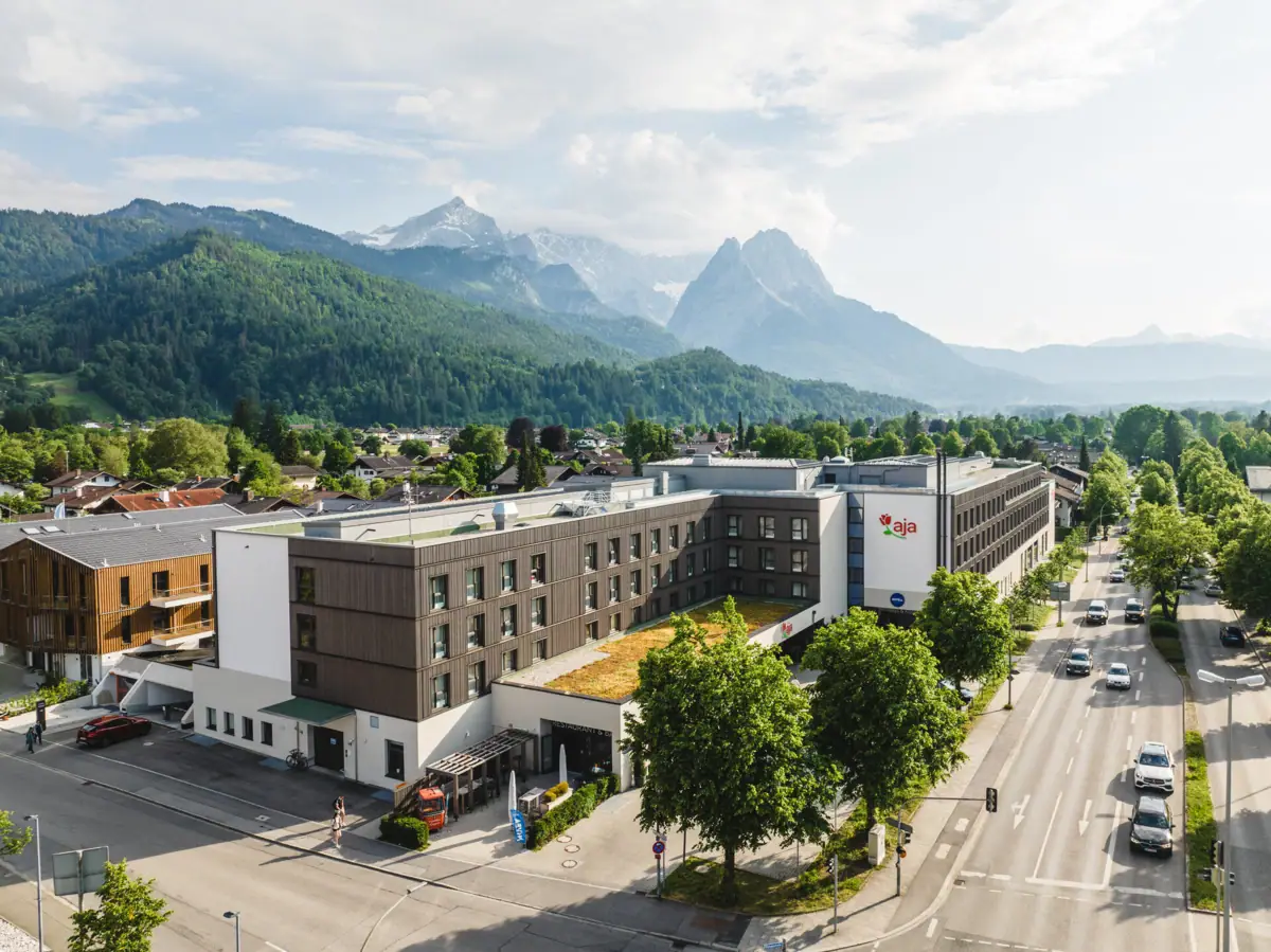 aja Garmisch-Partenkirchen A building with trees and mountains in the background.