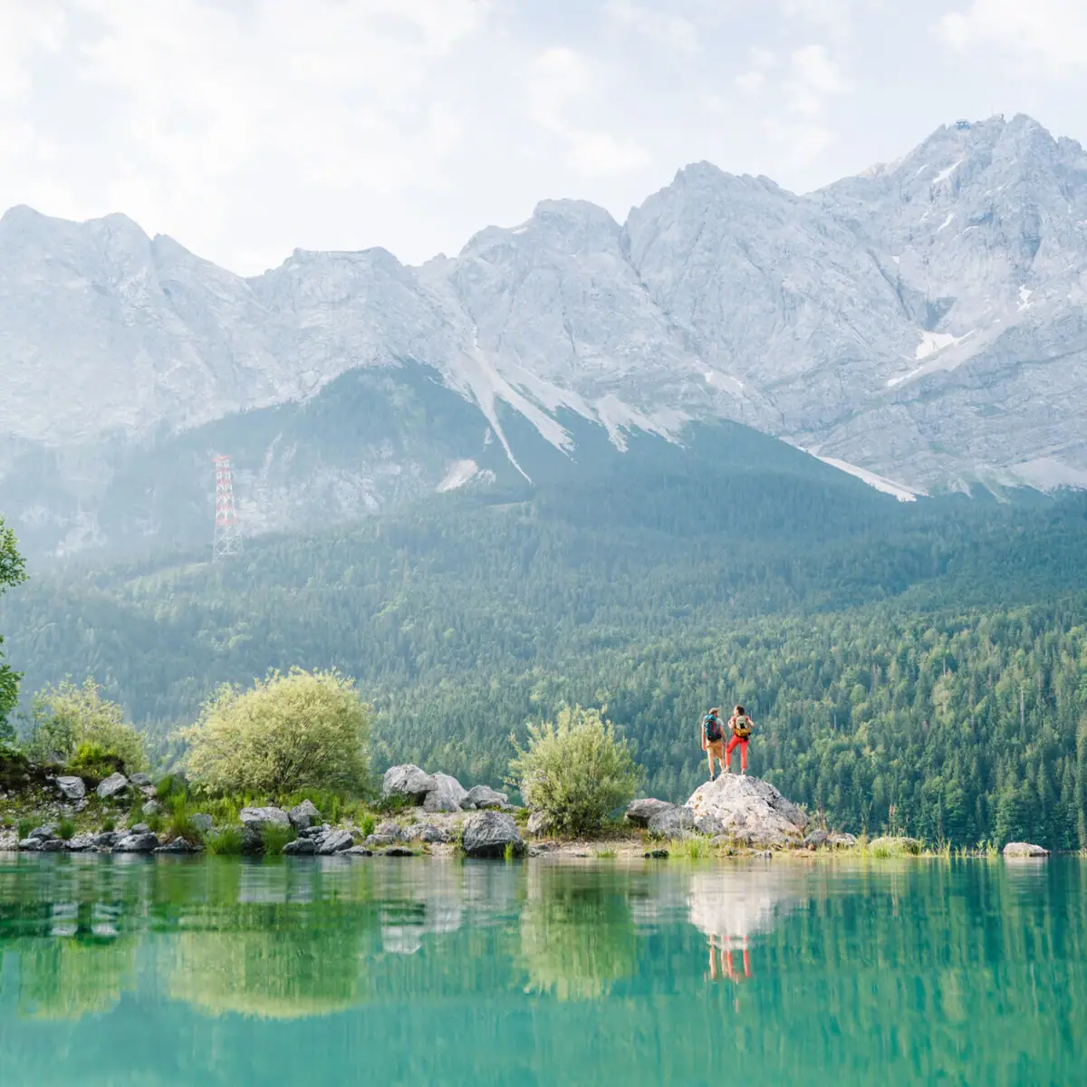 Eibsee People standing on a rock in front of a lake.