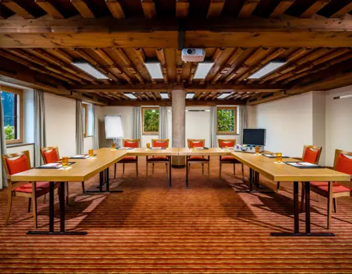 Conference area with U-shaped tables, chairs and windows.