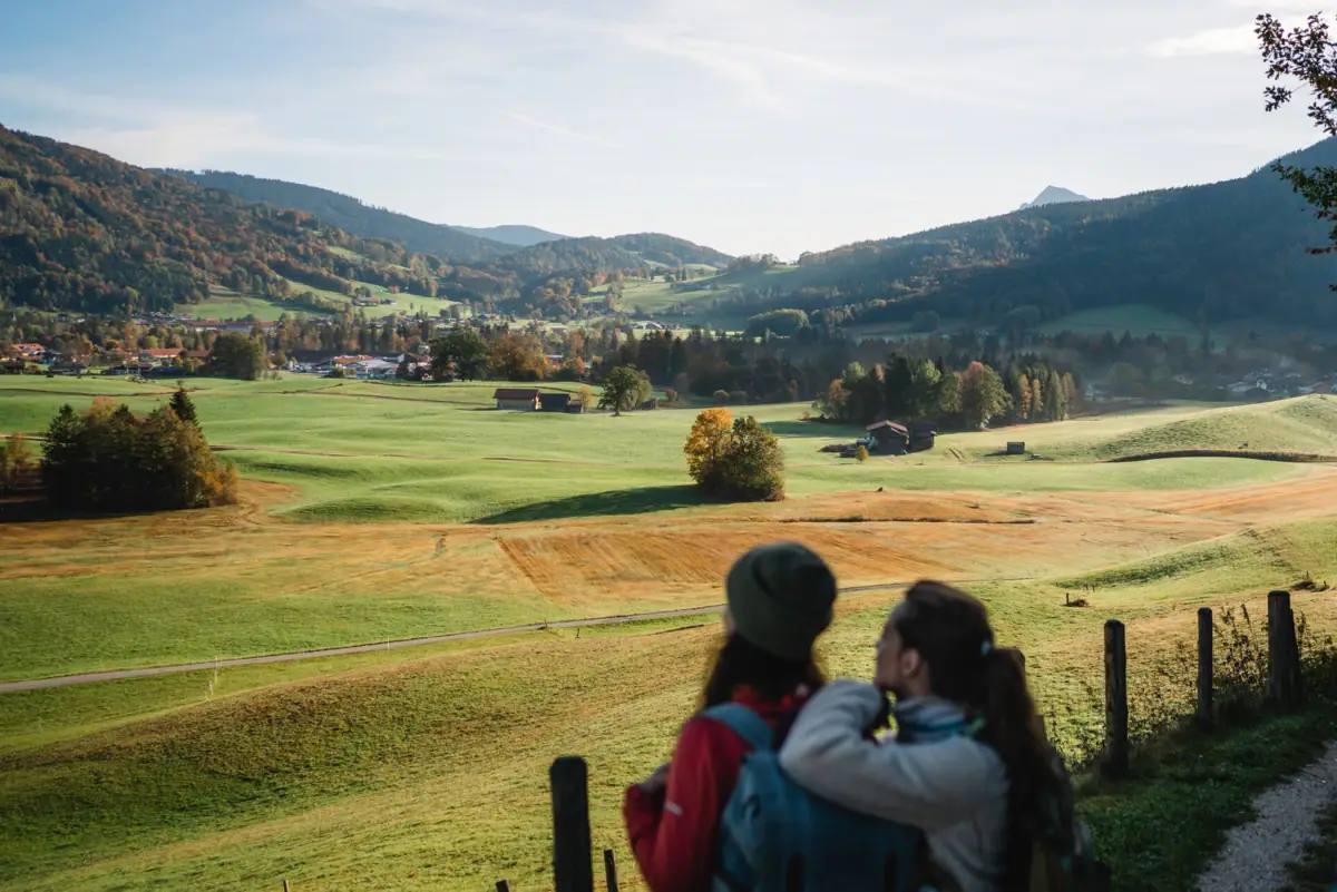 Two people are looking at a landscape with trees and clouds in the sky.