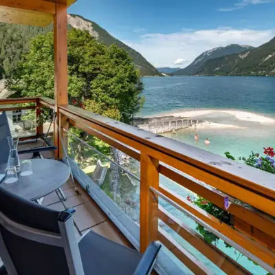 Balcony with a view of the lake A balcony with table and chairs overlooking a body of water.
