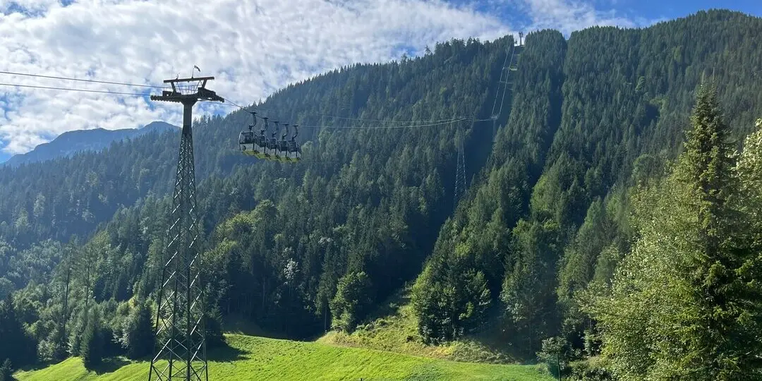 Cable car in front of a mountain panorama.