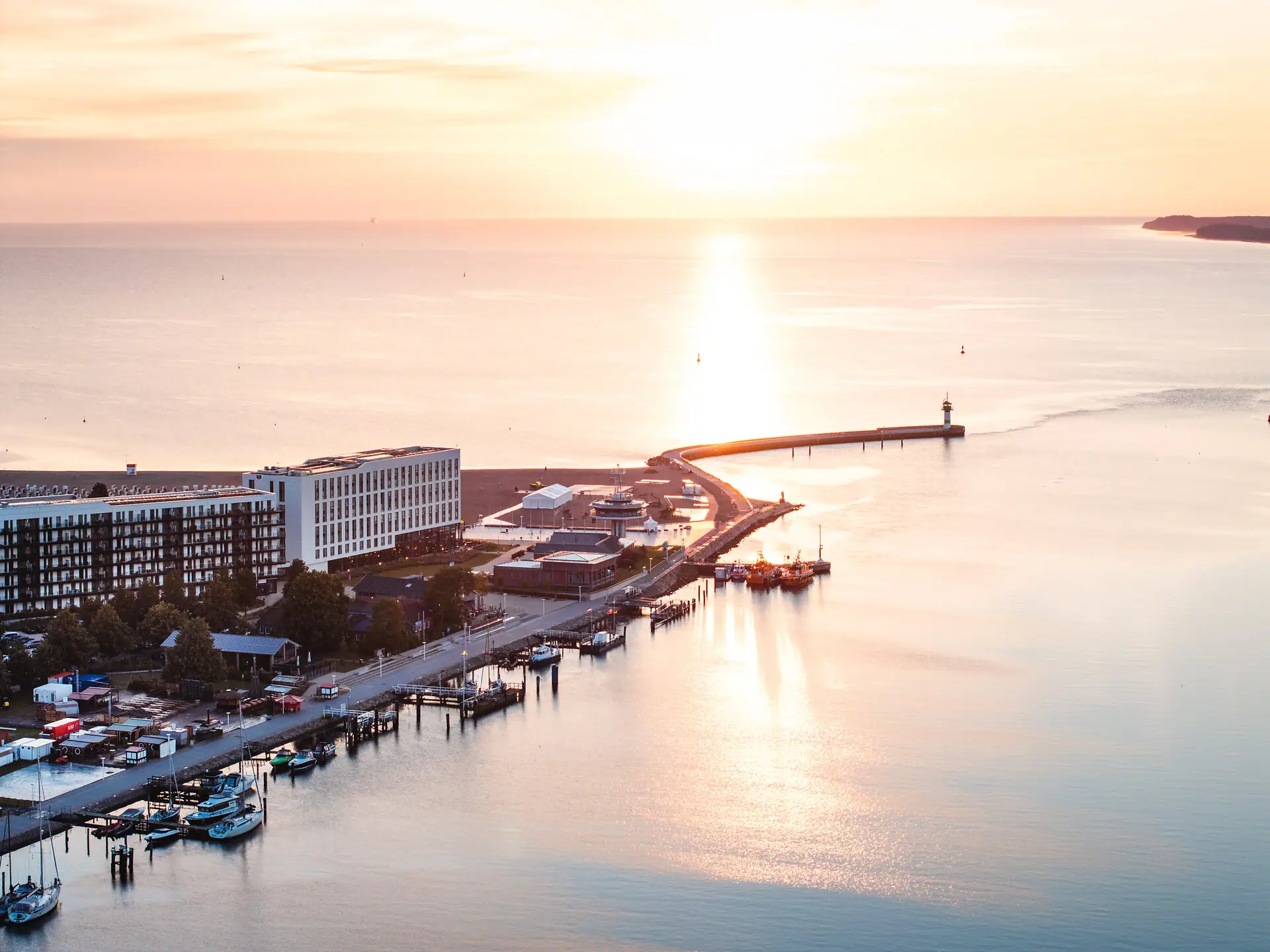 Das aja Travemünde direkt am Wasser gelegen mit einem Leuchtturm im Hintergrund.