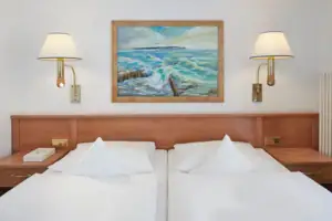 Comfort double room with balcony or terrace A bed with white sheets and a painting on the wall.