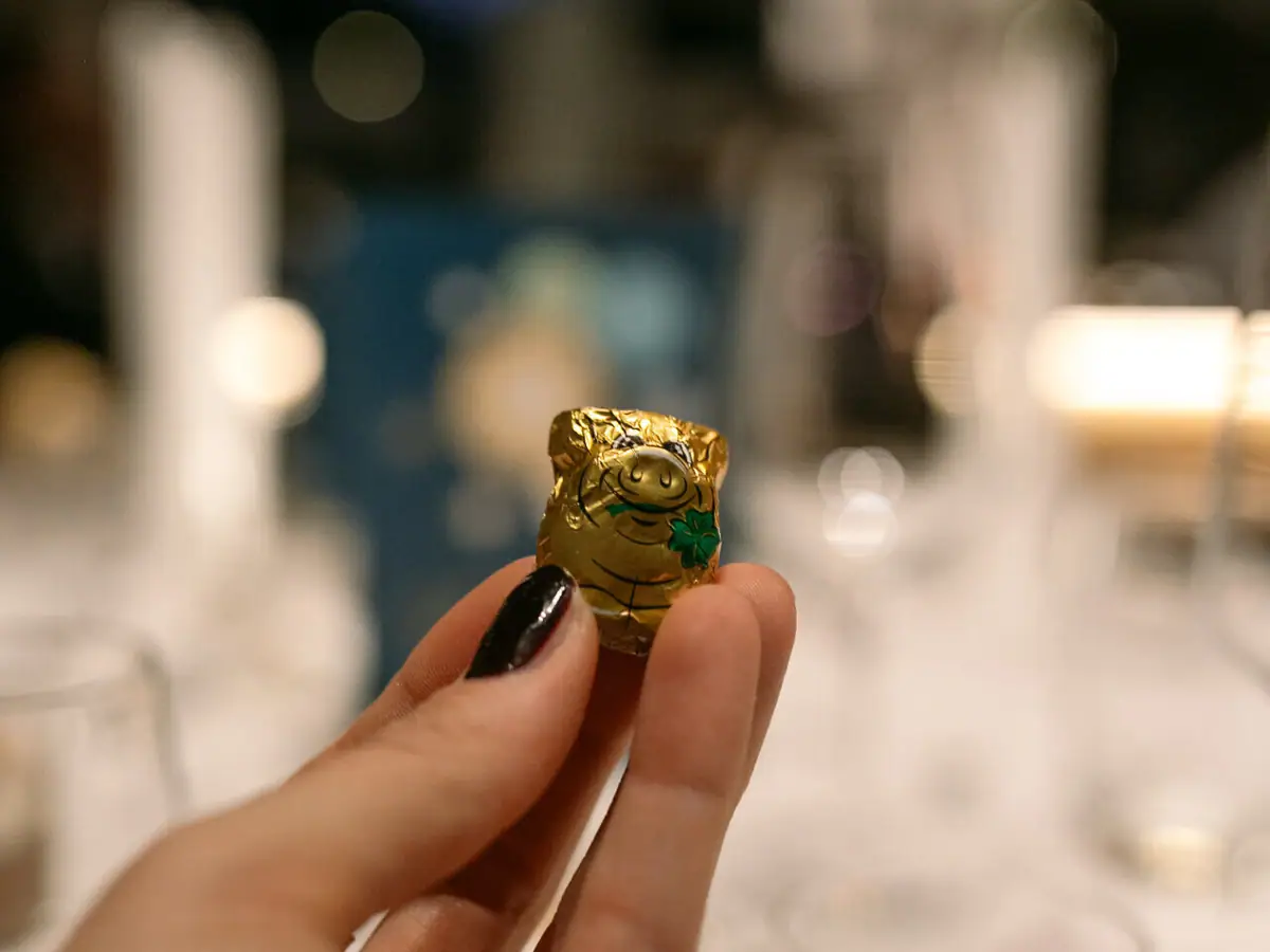 One hand holds a small wrapped chocolate pig.